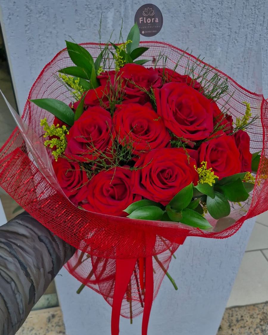 Buquê nº 09 — Clássico Vermelho: Uma dúzia de rosas vermelhas com folhagem e tango, finalizadas em tela vermelha — o presente atemporal